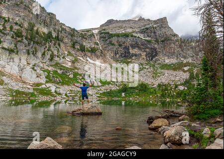 Wanderer stehen auf einem Felsen am Amphitheatre Lake im Grand Teton National Park, Wyoming, USA Stockfoto