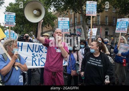 London, Großbritannien. Juli 2021. Die Krankenschwester David Carr wendet sich an NHS-Mitarbeiter, die vom St. Thomas' Hospital und dem UCH zur Downing Street marschierten, um gegen die Empfehlung des NHS Pay Review Body zu protestieren, eine Gehaltserhöhung von 3 % für NHS-Mitarbeiter in England zu fordern. Der protestmarsch wurde von Unite the Union, Das die ankommende NHS England-Chefin Amanda Pritchard aufgefordert hat, dafür zu sorgen, dass eine Erhöhung der NHS-Gehälter aus neuen Finanzmitteln und nicht aus bestehenden NHS-Budgets kommt, und von der in Kürze erwartet wird, dass sie ihren Mitgliedern eine beratende Abstimmung über Arbeitskampfmaßnahmen vorlegen wird. Kredit: Mark Kerrison/Alamy Live Nachrichten Stockfoto