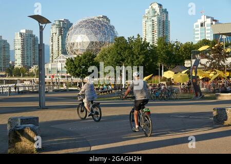 Ältere Männer und Frauen, die im Dorf False Creek, Vancouver, British Columbia, Kanada, mit ihren Fahrrädern unterwegs sind Stockfoto