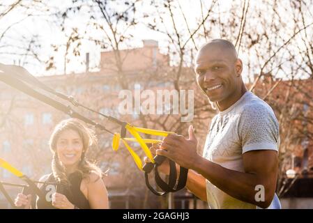 Fitness-Paar beim Training mit trx-Fitnessbändern im Park Stockfoto