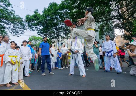 KALKUTTA, WESTBENGALEN, INDIEN - 29. MÄRZ 2015 : Weiß gekleideter Junge springt in der Luft, um zu treten, Karate zu pracieren - "Happy Street" Veranstaltung auf der Park Street, Kolk Stockfoto