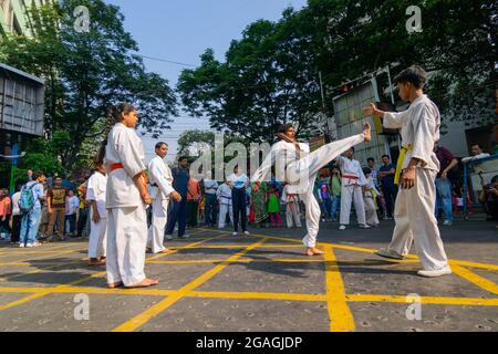 KOLKATA, WESTBENGALEN, INDIEN - 21. MÄRZ 2015 : Junge in weißem Kleid, der zum Kick vom Boden springt, Karate-Training bei der Happy Street-Veranstaltung im Park S Stockfoto