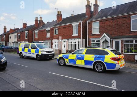 Polizeiwagen und -Van parkten vor einer Reihe von Häusern auf der Wyberton West Rd Stockfoto