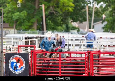 Ein Cowboy wischt sich die Stirn, nachdem er während einer Stierritt-Veranstaltung auf dem Noble County Fairgrounds in Kendallville, Indiana, USA, von einem Stier geworfen wurde. Stockfoto