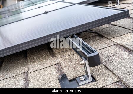 Schiene, Halterung und Anker an einem Solarpanel, das auf einem Asphaltschindeldach installiert ist Stockfoto