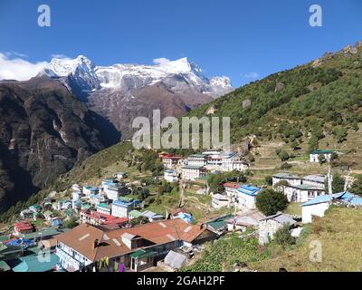 Blick auf die Berghänge der Stadt Namche Bazaar und die schneebedeckten Gipfel des Kongde Ri im Hintergrund, Solukhumbu District, Nepal Stockfoto