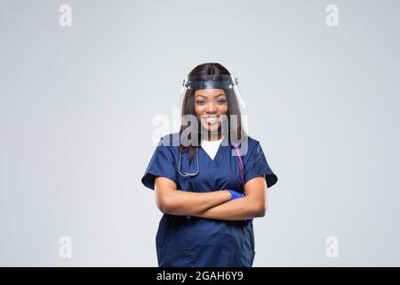 Porträt einer jungen schönen afrikanischen EMS-Ärztin, die Uniform und einen schützenden Gesichtsschutz trägt, der auf weißem Hintergrund isoliert ist. Stress und Stress Stockfoto