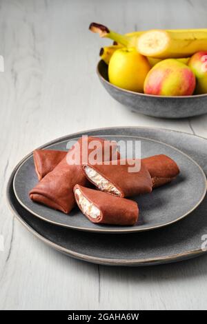 Dünne Schokoladenpfannkuchen gefüllt mit Ricotta, Banane und Apfel Stockfoto