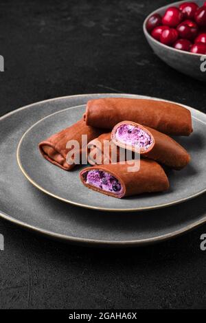 Dünne Schokoladenpfannkuchen gefüllt mit Quark, Heidelbeere und Kirsche Stockfoto