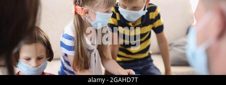 Kinder und Erwachsene spielen Brettspiele in schützenden medizinischen Masken Stockfoto