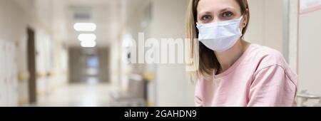 Porträt einer Frau in schützender medizinischer Maske sitzt im Krankenhaus Korridor Stockfoto