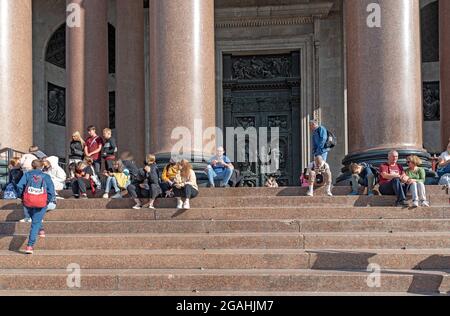 Sankt-Petersburg, Russland – 20. Juli 2021: Touristen sitzen nach der Exkursion auf der Treppe der Sankt-Isaak-Kathedrale Stockfoto