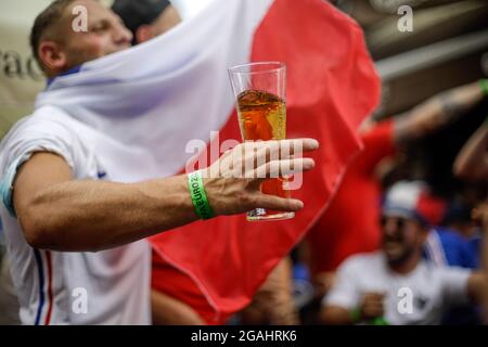 Bukarest, Rumänien - 23. Juli 2021:Bild mit geringer Schärfentiefe (selektiver Fokus) mit einem Euro 2020-Fan, der ein Bier hält und während eines Fußbeines feiert Stockfoto