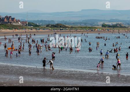 Menschenmassen im Meer bei einem Aufenthalt in troon in schottland, Schwimmer, Badegäste, Menschen, die im Meer schwimmen, Menschenmassen am Meer, Menschenmassen bei heißem Sommerwetter Stockfoto