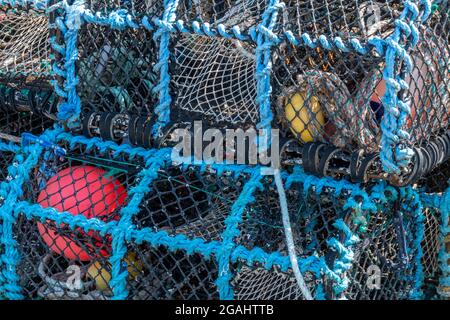 Hummertöpfe trocknen am Kai, abstrakte Hummertöpfe, Hummer- und Krabbentöpfe und Netze trocknen an einer Hafenmauer aus, Netze abstrakt, Hintergrund. Stockfoto