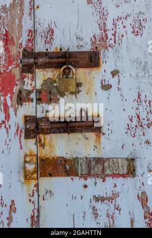 Rostige alte Scharniere an einer alten bemalten Tür, schäbige schicke Tür mit abblätternder Farbe und korrodierten Scharnieren, Texturen, Struktur, Holztür mit verrosteten Scharnieren. Stockfoto