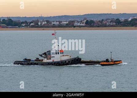 Schlepper, der an einem Lastkahn im solent befestigt ist, Schlepper, der auf dem Meer schleppt, Schlepper in portsmouth, der unleistungsfähige Lastkahn bewegt, Schlepper, der Ponton auf dem Meer bewegt. Stockfoto