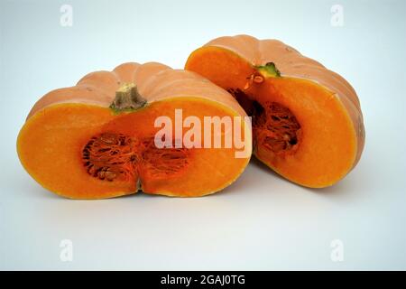 Nahansicht von Butternut-Kürbis oder Kürbis, der in zwei Hälften isoliert und mit viel Kopierraum geschnitten wurde. Saisonales Gemüse in leuchtendem Orange. Stockfoto