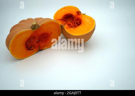 Ein Butternut-Kürbis oder Kürbis, der in zwei Hälften getrennt und mit viel Platz zum Kopieren ausgestattet ist. Saisonales Gemüse in leuchtendem Orange ist kontrastreich. Stockfoto