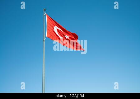 Plätschernde türkische Flagge auf windigem, blauem Himmel. Hochwertige Fotos Stockfoto