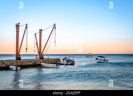 Szenischer Sonnenuntergang mit Booten am Wasser. Moutsouna ist ein winziges, malerisches Fischerdorf auf der Insel Naxos, den Kykladen und der Ägäis. Stockfoto