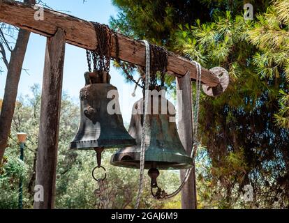 Zwei alte Glocken hängen vor der kleinen Kapelle von Agios Dimitrios Loubardiaris, die sich am Fuße des Nymphenhügels in Athen befindet. Stockfoto