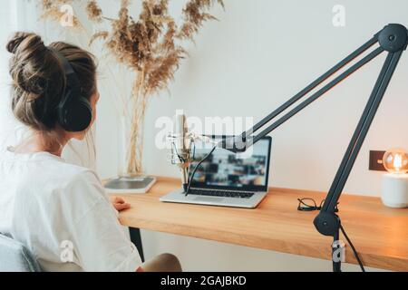 Rückansicht einer jungen Frau, die Podcast im Heimstudio aufnimmt. Weibliche Podcasterin, die in das Mikrofon sendet Stockfoto
