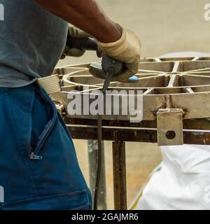 Schlosser in Spezialkleidung arbeiten in der Produktion. Metallbearbeitung mit Winkelschleifer. Funken in der Metallbearbeitung. Stockfoto