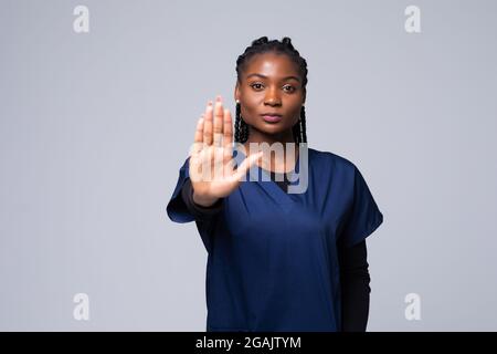 Junge schöne afroamerikanische Ärztin tut Stop-Geste mit Handfläche. Warnausdruck mit negativer und ernsthafter Geste auf dem fa Stockfoto