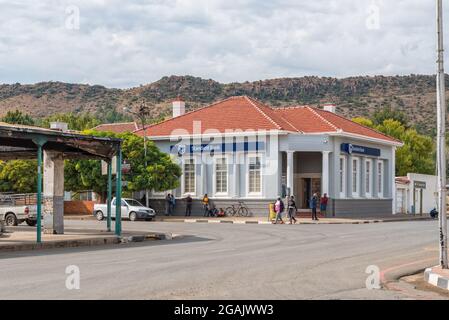 BURGERSDORP, SÜDAFRIKA - 22. APRIL 2021: Eine Straßenszene mit einem Bankgebäude, Menschen und Fahrzeugen in Burgersdorp in der Provinz Eastern Cape Stockfoto