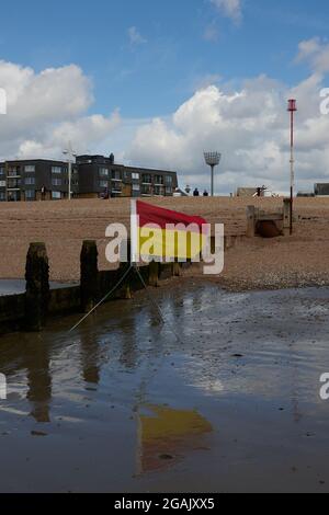 Rote und gelbe RNLI-Rettungsfahne am Strand. Stockfoto