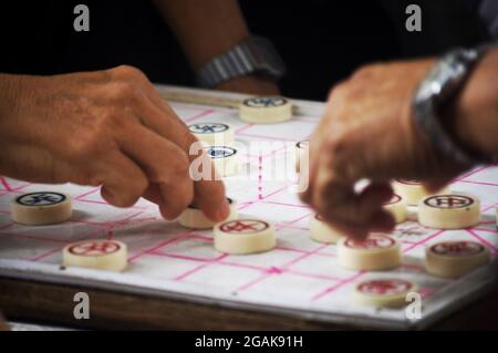 Vietnamesische Männer spielen im Freien neben der Straße auf dem Dong Kinh Nghia Thuc Square in Hoan ein Wettspiel mit chinesischem Schach oder Xiangqi-Elefantenschach Stockfoto