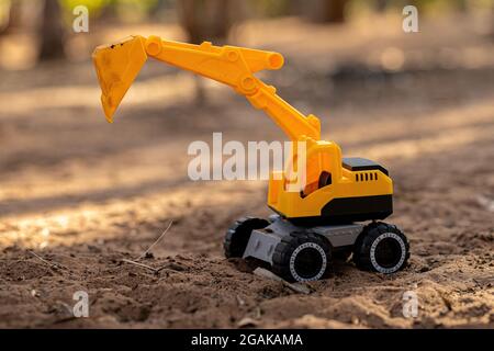 Gelbe und schwarze Farbe Spielzeug Bagger Miniatur auf dem Boden mit selektivem Fokus Stockfoto