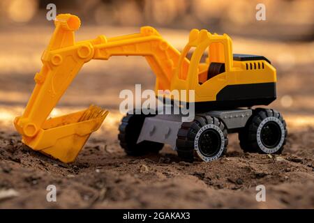 Gelbe und schwarze Farbe Spielzeug Bagger Miniatur auf dem Boden mit selektivem Fokus Stockfoto