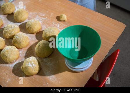 Mujer caucásica masando masa para hacer pan y bizcochos en una mesa color madera con luz de día, en una panadería. Stockfoto