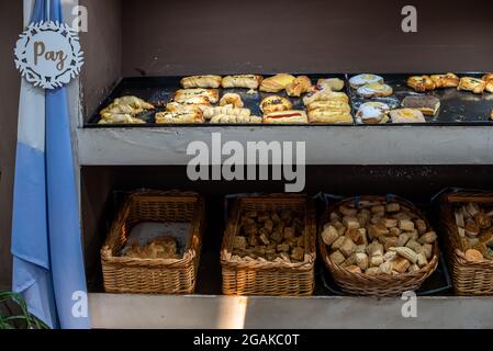 Mujer caucásica masando masa para hacer pan y bizcochos en una mesa color madera con luz de día, en una panadería. Stockfoto