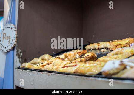 Mujer caucásica masando masa para hacer pan y bizcochos en una mesa color madera con luz de día, en una panadería. Stockfoto