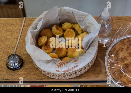 Mujer caucásica masando masa para hacer pan y bizcochos en una mesa color madera con luz de día, en una panadería. Stockfoto