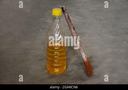 Nahaufnahme der gelben Farbe Teer Peen Plastikflasche mit altem Pinsel über Out of Focus grauen Hintergrund. Stockfoto