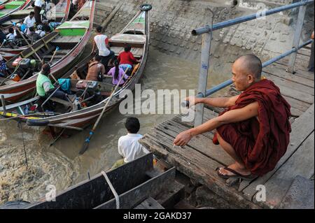 30.01.2014, Yangon, Myanmar, Asien - Flusstaxis warten am nördlichen Ufer des Yangon-Flusses, während ein buddhistischer Mönch eine Zigarette raucht, während er wartet. Stockfoto
