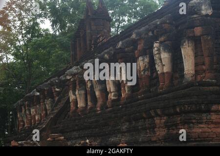 Eine Reihe von Elefantenstatuen um einen Chedi (Basis) eines alten Tempels im Kamphaeng Phet Historical Park, Thailand Stockfoto