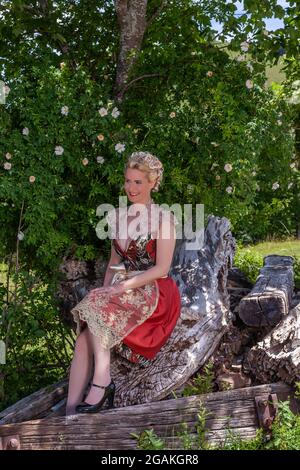 Portrait einer blonden Frau im Dirndl, in einer romantischen Kulisse in den Bergen Stockfoto