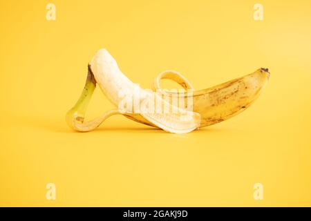 Nahaufnahme einer geschälten reifen Banane, isoliert auf gelbem Hintergrund Stockfoto