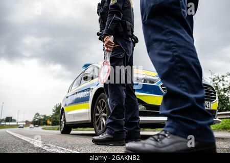 Emmerich, Deutschland. Juli 2021. Polizeibeamte stehen bei einer Corona-Einreisekontrolle durch die Bundespolizei an der deutsch-niederländischen Grenze mit einem Polizeistoppstock und kontrollieren Fahrzeuge im Grenzgebiet. Quelle: Guido Kirchner/dpa/Alamy Live News Stockfoto