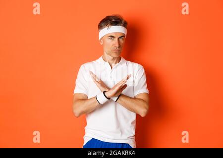Konzept von Sport, Fitness und Lifestyle. Porträt eines ernsthaft aussehenden männlichen Trainers mit Kreuzzeichen, zu sagen, zu stoppen, etwas zu verbieten und auszudrücken Stockfoto