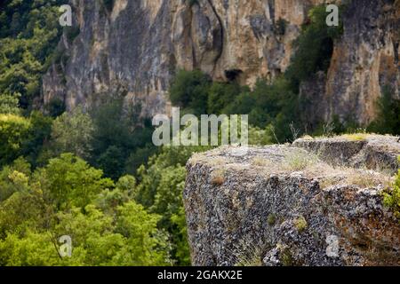 Nahaufnahme eines großen Felsens in den Bergen mit einer weiteren großen Klippe im Hintergrund in den bulgarischen Bergen. Selektiver Fokus. Stockfoto