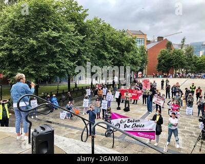 Menschen halten Plakate und Banner hoch, während sie an einer Wahlkampfveranstaltung auf dem Writer's Square in Belfast teilnehmen. Wahlkämpfer und Abtreibungsgegner haben in Belfast separate Proteste abgehalten, inmitten des sich verschärfenden politischen Streites über die Beauftragung von Diensten in Nordirland. Bilddatum: Samstag, 31. Juli 2021. Stockfoto