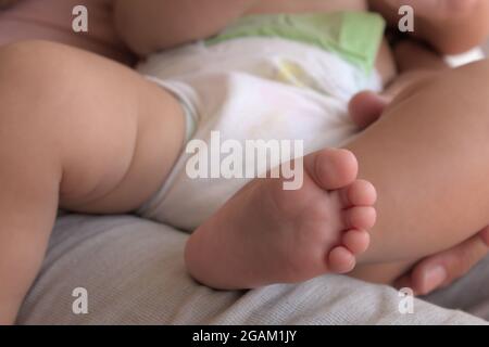 Vordergrund eines Fußes eines Babys auf einem Schoß seines Vaters Stockfoto