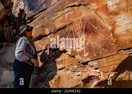 Karen Rentz mit einer spektakulären Tafel einer stilisierten menschlichen Figur auf der McKee Spring Petroglyph Site, Dinosaur National Monument, Utah, USA Stockfoto