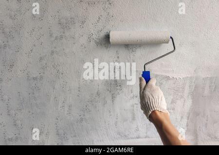 Ein Mädchen malt eine Wand mit weißer Farbe. Hand mit Walze für Nahaufnahme mit Kopierraum Stockfoto